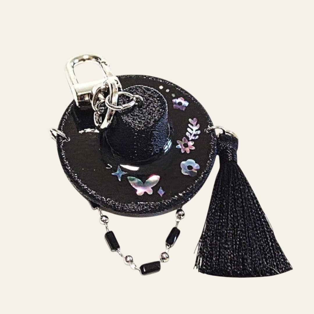 HanPorta black resin Gat hat keyring with iridescent mother-of-pearl butterfly inlay, beaded strap, and black tassel.